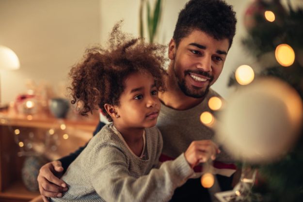 3 Tips For a Sober Holiday child being held decorating a tree thanks to parent having a sober holiday