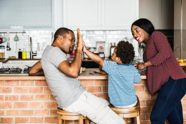 5 Goals for Successful Family Therapy a kid high-fives a parent while another parent looks on after setting goals for successful family therapy