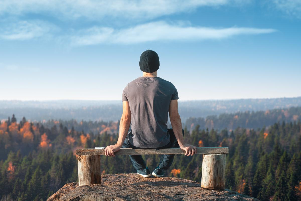 3 Mental Health Tips For Life After Rehab a person sits on a bench overlooking a mountain and forest during life after rehab