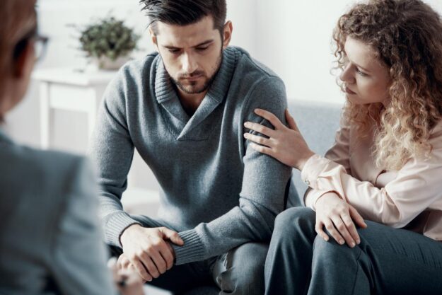 Signs of Heroin Addiction in a Loved One a couple comforts each other as they talk to a therapist about signs of heroin addiction
