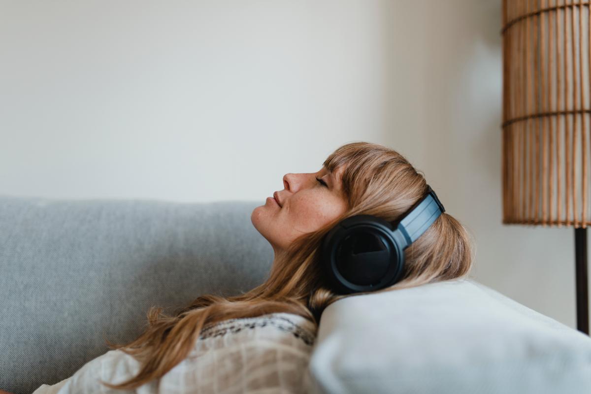 5 Songs About Overcoming Addiction woman laying on bed with headphones listening to 5 songs about overcoming addiction