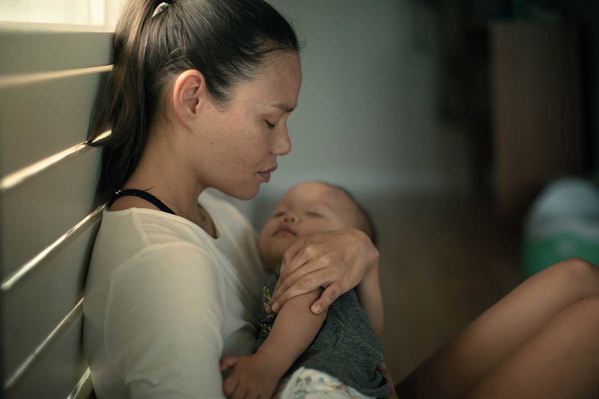 Postpartum-Depression-How-Long-Does-It-Last-and-How-to-Get-Help a person looks sad while holding a baby and wondering how long does postpartum depression last