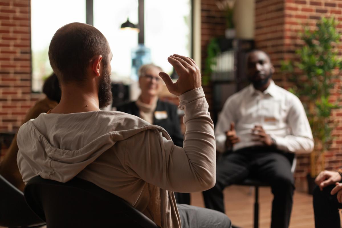 a person raises their hand in a group therapy session in residential treatment near West Chester