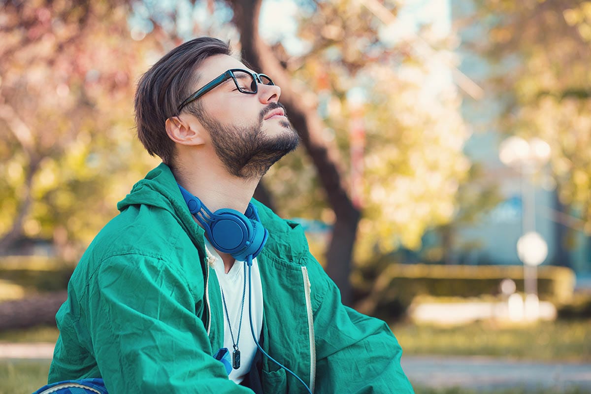 a person sits outside in a park performing self calming exercises for anxiety