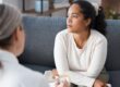 a person looks forlorn while sitting on a couch and learning about the benefits of an anxiety treatment center