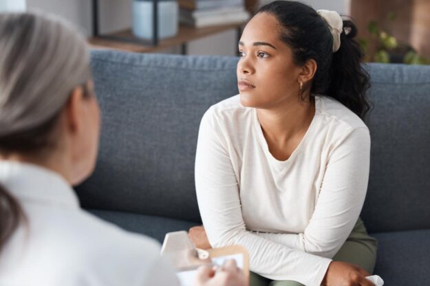 Benefits of an Anxiety Treatment Center a person looks forlorn while sitting on a couch and learning about the benefits of an anxiety treatment center