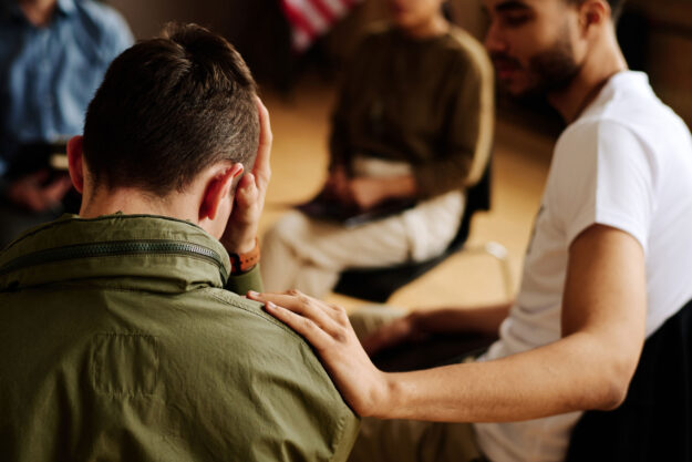 Common Signs of PTSD A group of people in therapy discuss signs of PTSD