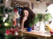 A woman eats cookies in front of the Christmas tree while she takes a break from her family. She's navigating holiday triggers.