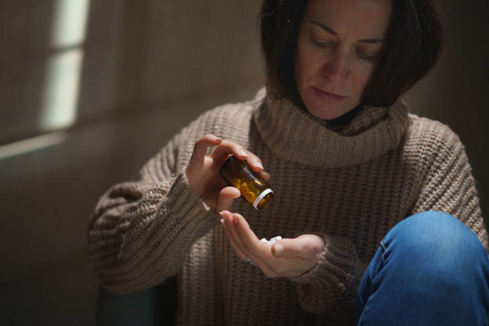 a woman pouring a handful of opioids in her hand