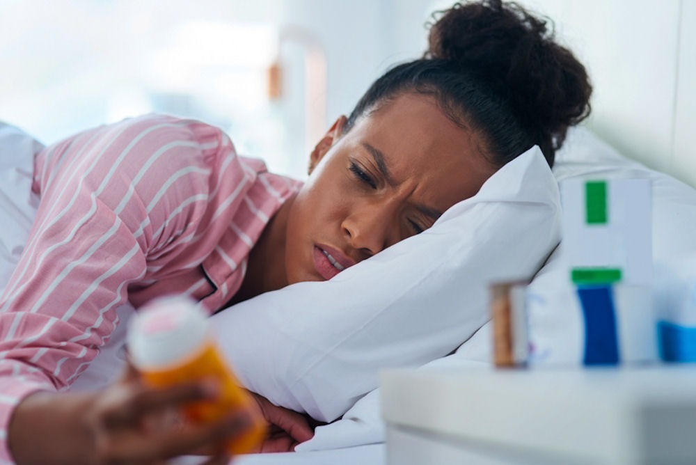 a woman laying in bed holding a bottle of opioids