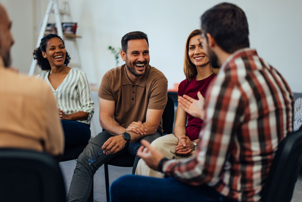 a group of individuals laughing and smiling in therapy